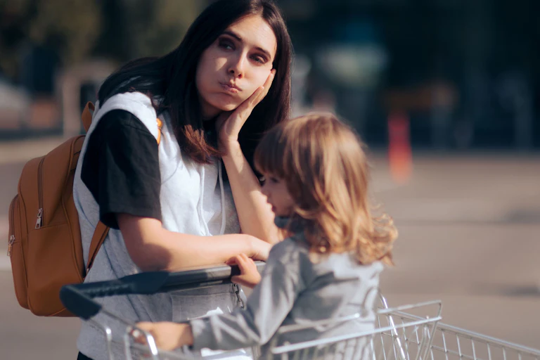Mother looking tired with child in supermarket trolley