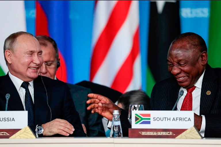 Two men wearing suits and ties share a laugh.
