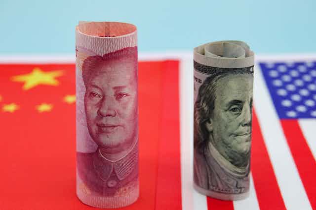 Rolled up 100-yuan and 100-dollar bills set atop Chinese and U.S. flags