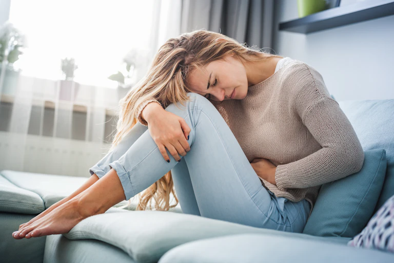 A woman clutches her stomach in pain.