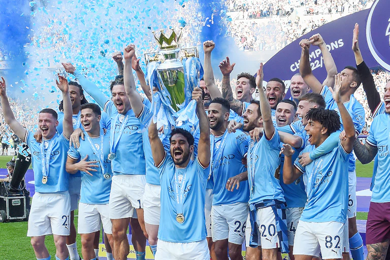 Manchester City in blue shirts holding the Premier League trophy aloft