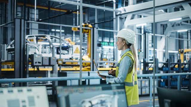 An engineer with a laptop looking at a car production line.