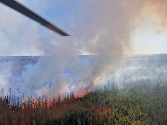 photo taken from a plane or helicopter showing a forest fire burning in the distance