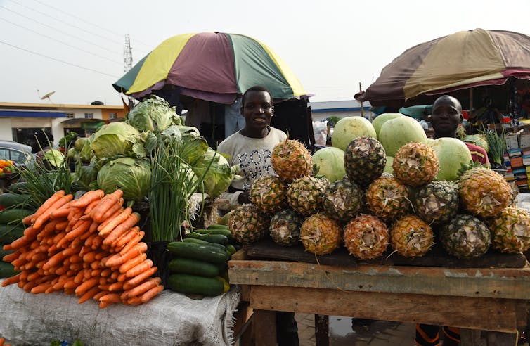 men standing behind piles of fruits and vegetables arranged on tables