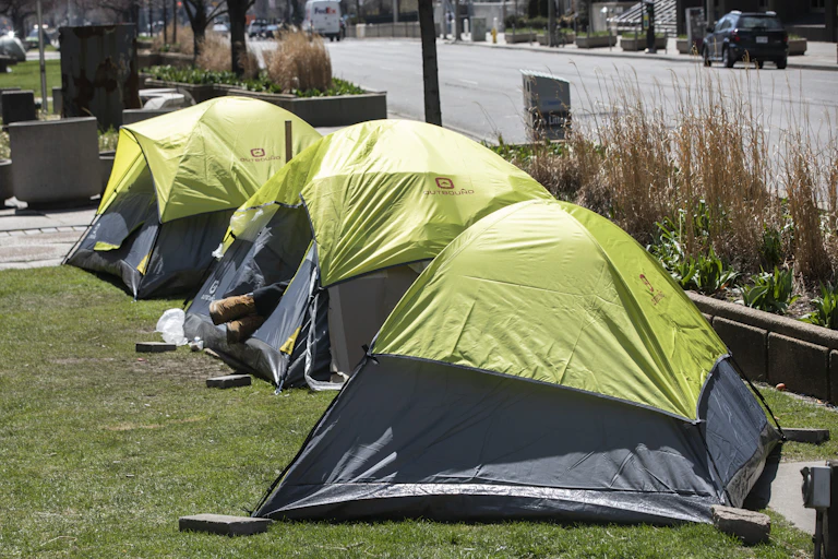 Three bright green tents are seen in a row, a person's feet sticking out of one of them.