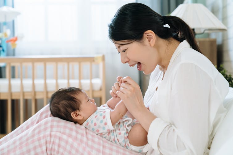 A woman smiling and playing with her baby in her lap