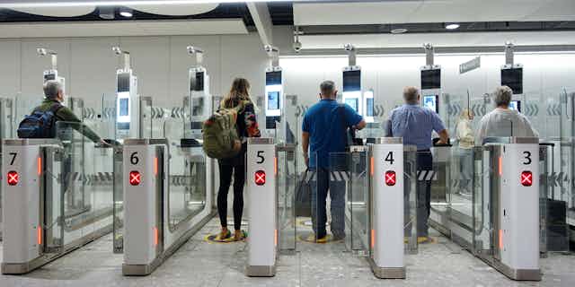 View from behind of people walking through the electronic passport gates at a UK airport
