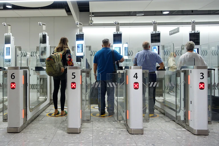 View from behind of people walking through the electronic passport gates at a UK airport