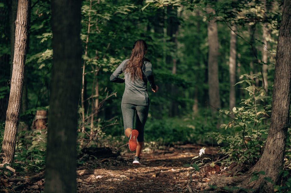 A woman goes for a run in a forest.