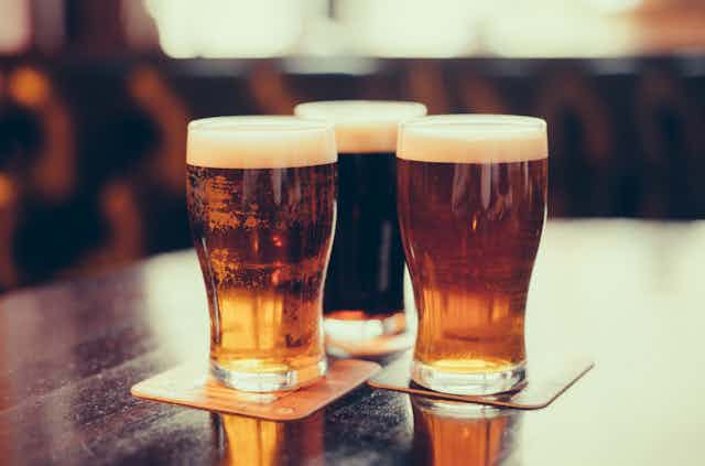 Three pints of beer on a bar.