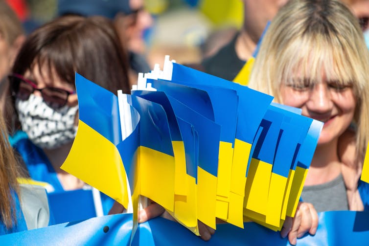 Two women at a march holding a handful of small Ukrainian flags