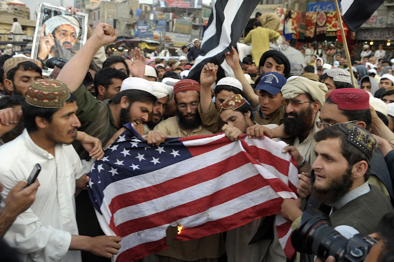 Des manifestants au Pakistan, avec un portrait de Ben Laden, en train de brûler un drapeau américain