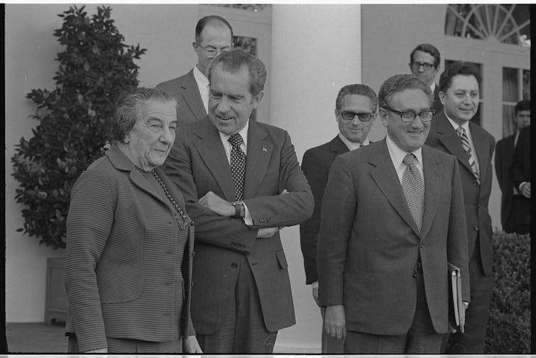 Henry Kissinger, Richard Nixon and Golda Meir stood smiling with aides.