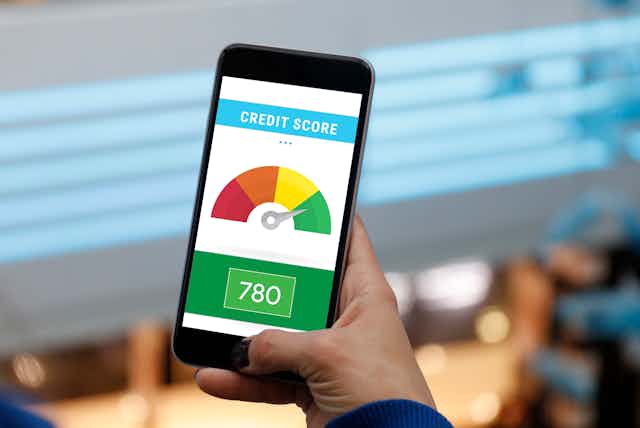 what is credit assignment problem A man holds a smartphone showing an image of an individual's credit score in the green zone on a continuum from red to green..