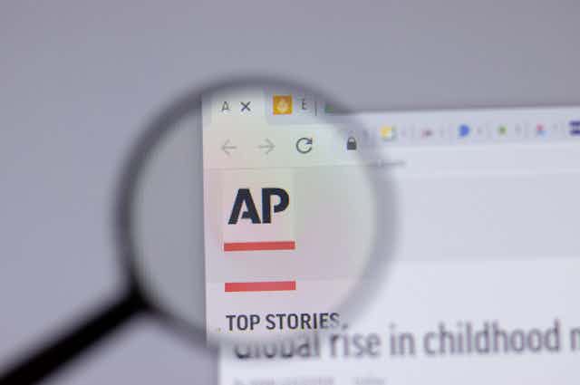 A magnifying glass hovering over the AP logo on the Associated Press news website