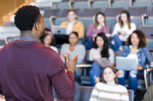 A professor teaching a group of students sitting in front of him.