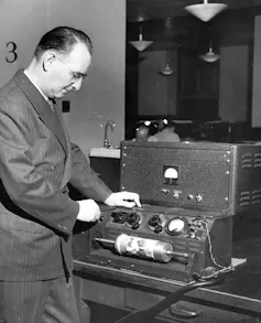 A black-and-white photo of a man operating a wire service machine