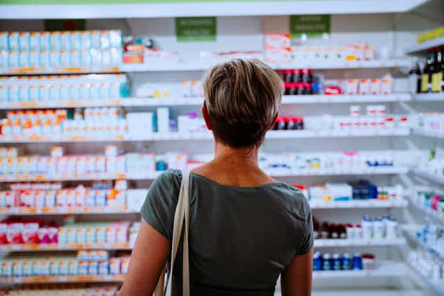 woman looks at shelves of pills and supplements