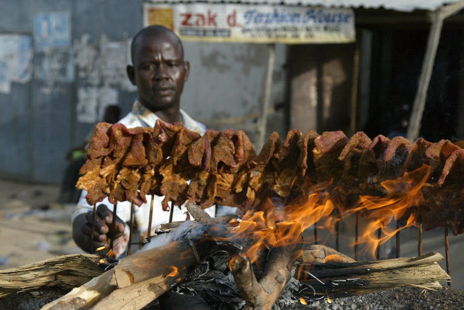 A man arranges sticks of meat on a mud platform