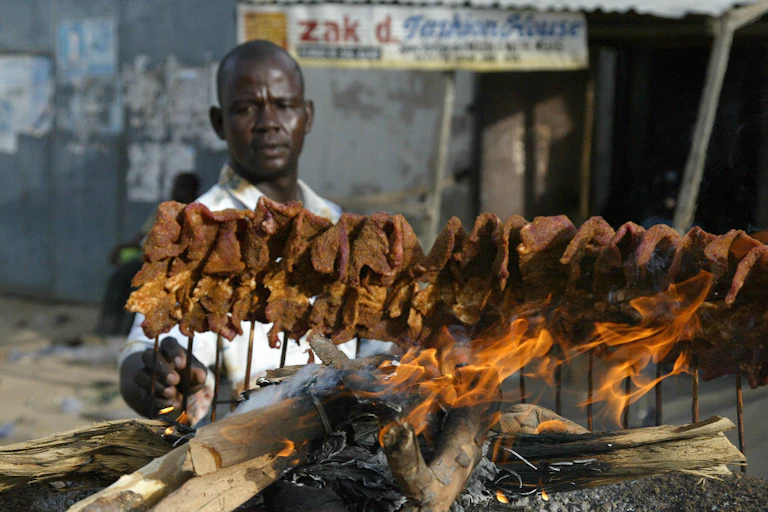 A man arranges sticks of meat on a mud platform