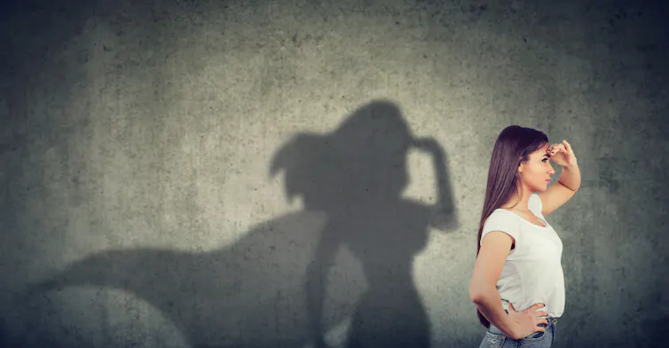 Jeune femme qui regarde vers l'avenir et son ombre sur le mur