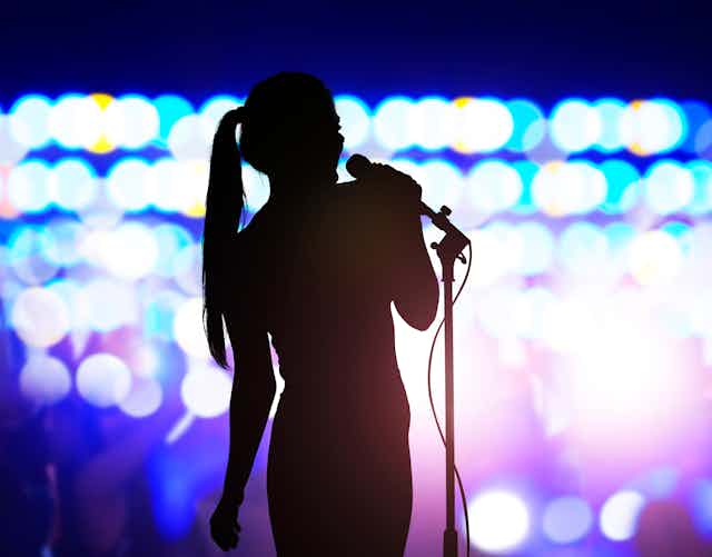 woman silhouetted on stage with mic