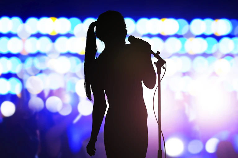 woman silhouetted on stage with mic