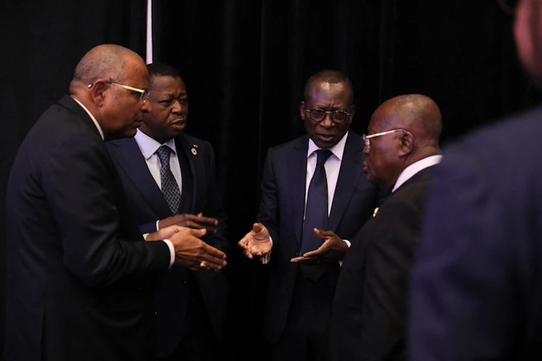 Four men stand together talking