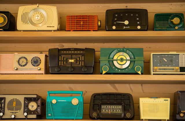 Three shelves of vintage radios.