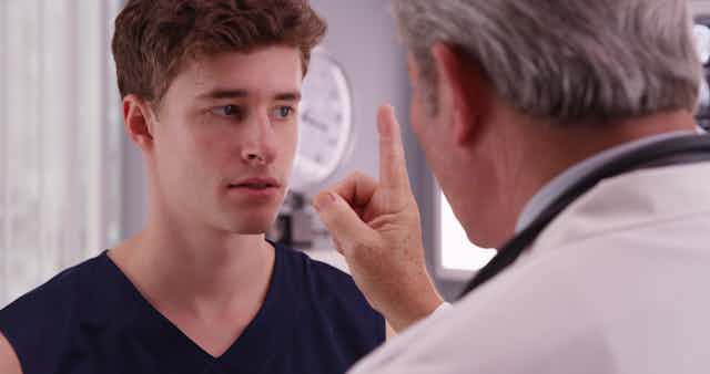 young man with doctor testing his eye tracking