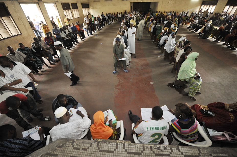 People sitting on a queue inside a hall