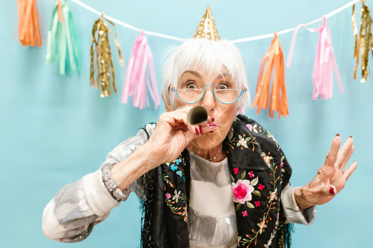 Older woman at a party blowing a party horn.