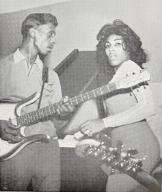 Ike and Tina Turner holding guitars in a black and white photograph.
