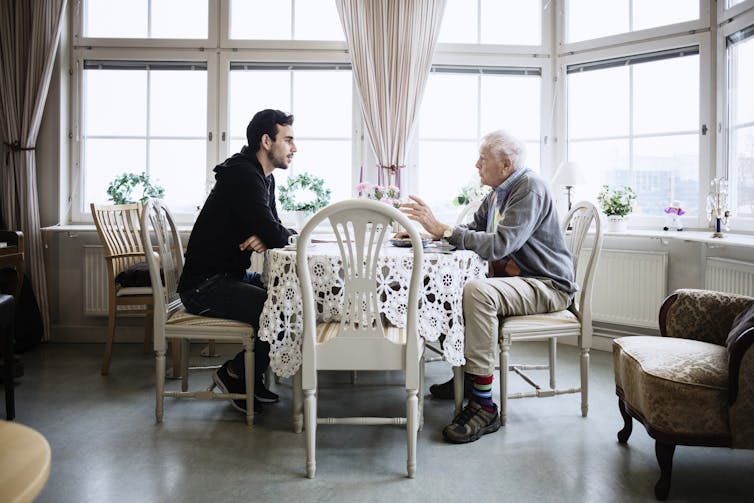 homem mais jovem e mais velho em discussão na mesa de jantar