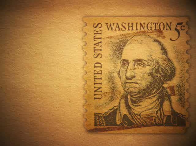Against an antique brown background: a U.S. postage stamp featuring an image of George Washington.