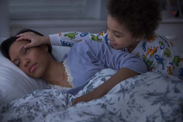 Young child wakes up sleeping mother
