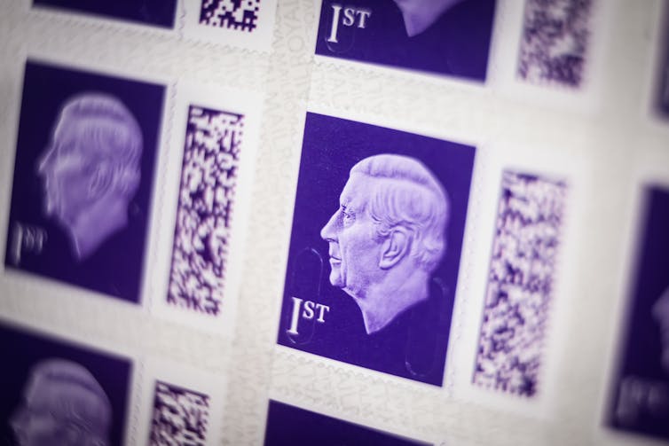 Against a purple background, an image of King Charles III, depicted in profile, facing left, and without a crown, appears on a UK postage stamp.