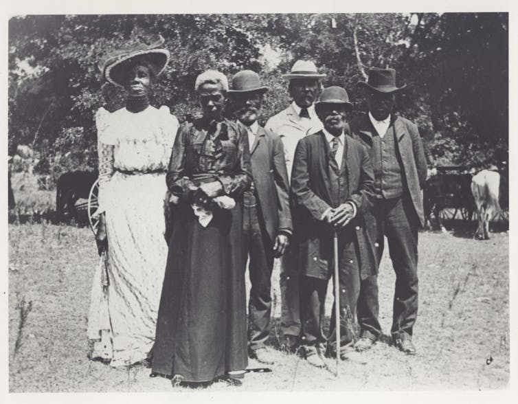 Six older African Americans face the camera in a photo from the year 1900.