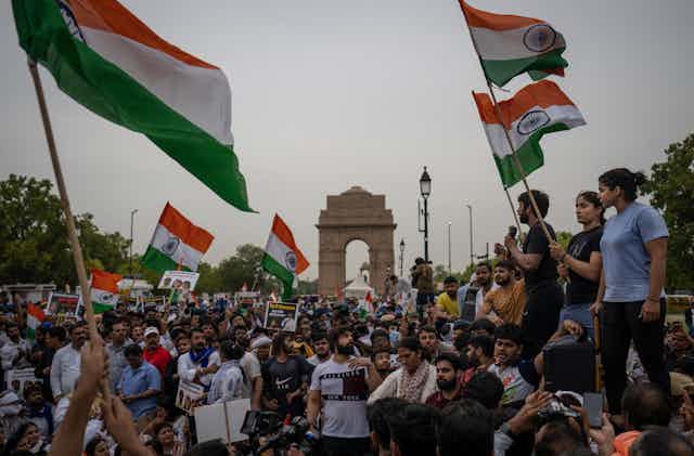 People march down a street waving Indian flags.