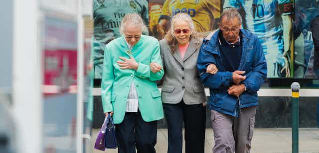 Three older people cross the street