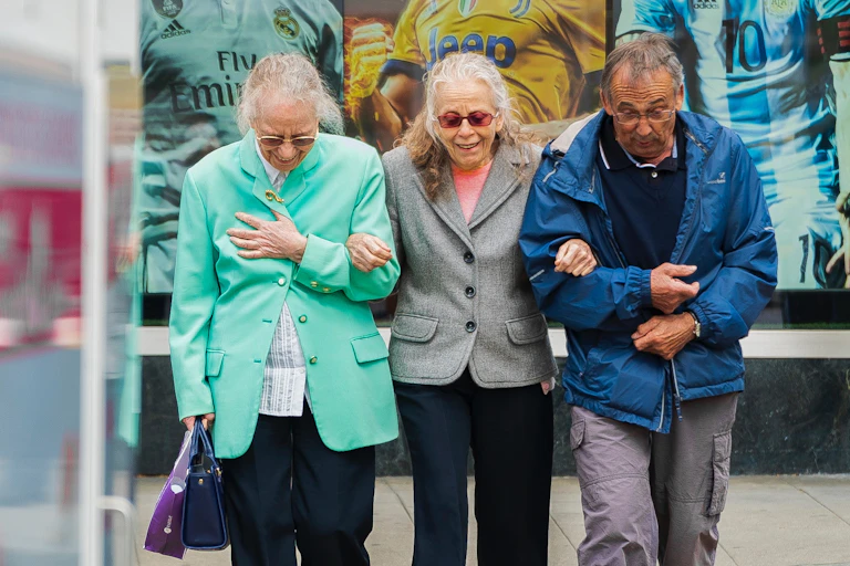 Three older people cross the street