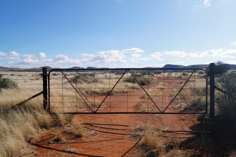 Closed farm gate across dirt track