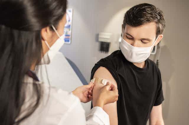 Clinician puts bandaid on patient after a vaccination