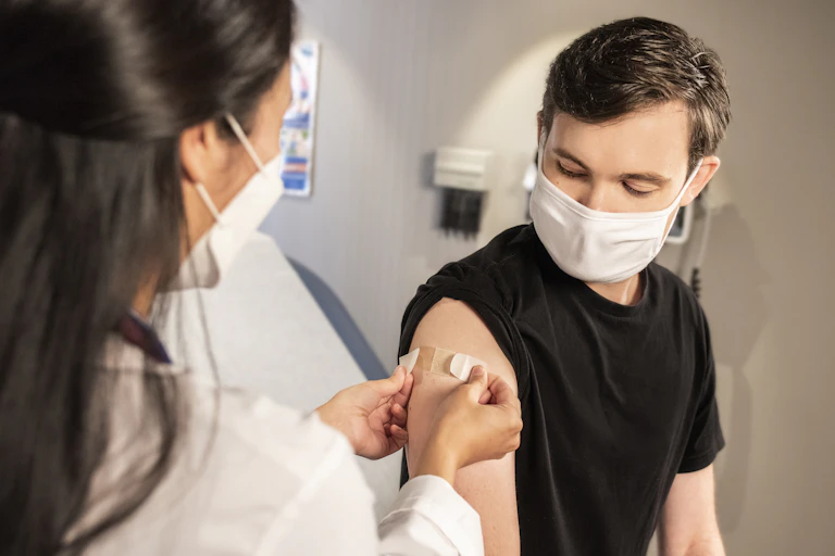 Clinician puts bandaid on patient after a vaccination