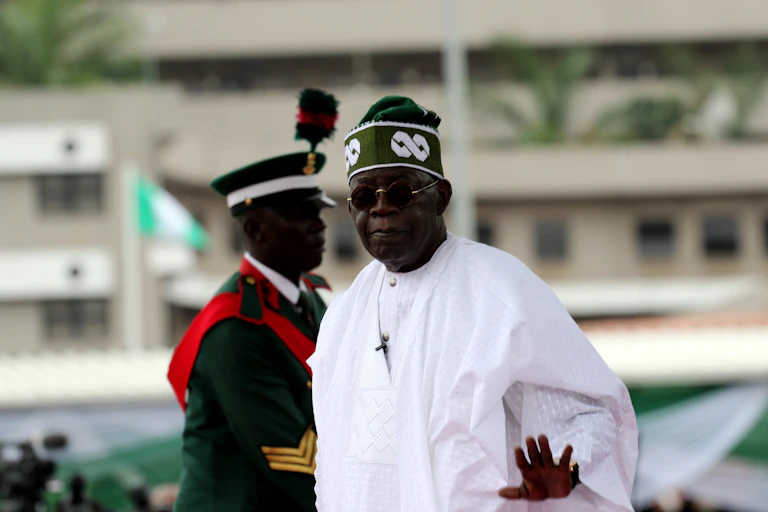A man wearing white dress with traditional cap in front of a military officer in ceremonial uniform