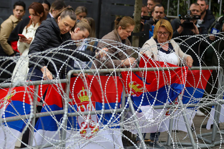 Serbian women attach a Serbian flag to a barbed wire barrier in the town of Zvecan, northern Kosovo, May 31 2023
