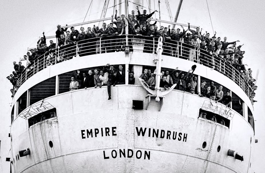 A large white ship called Empire Windrush carrying migrants from the Caribbean to London, with people on deck waving and cheering.