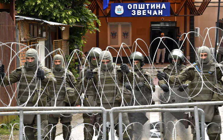SOldiers from Nato's KFOR peacekeeping force putting up barbed wire across a street in Kosovo.