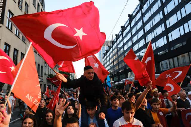 Young people waving large red Turkish flags.