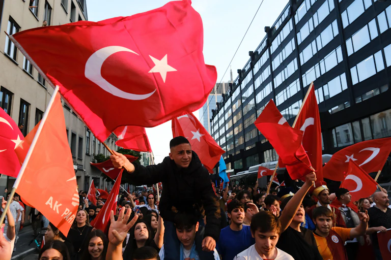 Young people waving large red Turkish flags.